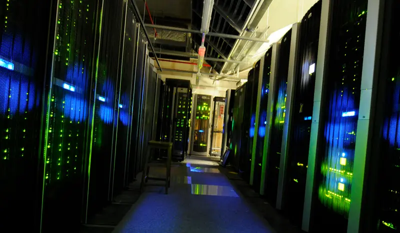 Aisle between server racks lit in blue and green